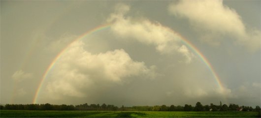 Full rainbow between clouds